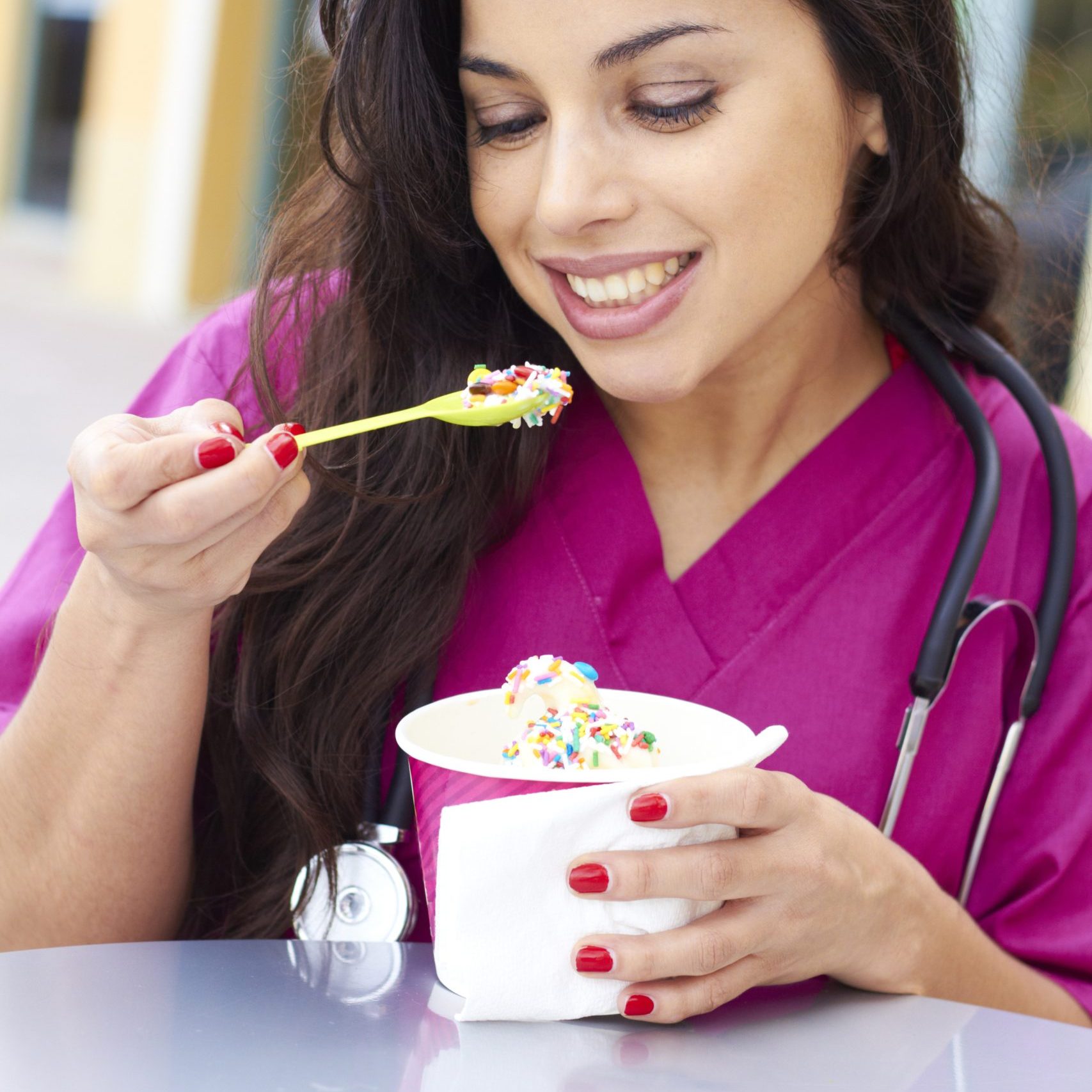 happy young beautiful female doctor eating frozen yogurt